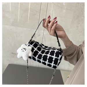 Detail of checkered tweed bucket bag featuring leather strap and plush star charm