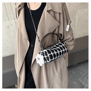 Detail of checkered cylinder bag featuring a plush dog charm and chain strap