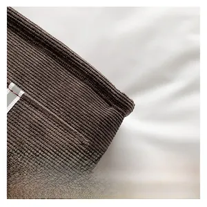 Close-up of deep brown corduroy fabric texture with a white woven label detail