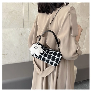 Detail of checkered tweed cylinder bag with leather strap and plush cloud charm