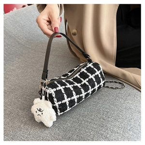 Detail of checkered cylinder bag featuring chain strap and cute white bear charm