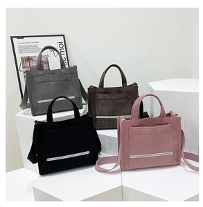 Close-up of corduroy tote bags in gray, brown, black, and pink colors on white stands