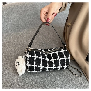 Detail of checkered tweed cylinder bag with gold hardware and plush bear charm decoration