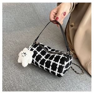 Detail of black and white plaid tweed cylinder bag with gold chain and plush star charm