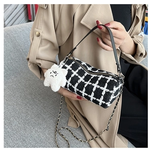 Detail of checkered barrel bag with black leather handle and plush star pendant charm