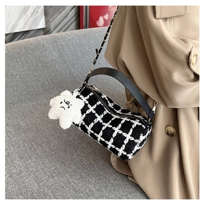 Detail of checkered tweed cylinder bag with black leather handle and star charm