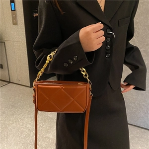 Vintage brown quilted crossbody bag with gold chain strap on a black blazer