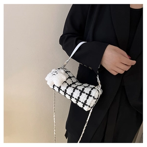 Detail of tweed checkered crossbody bag with white leather handle and plush bear charm