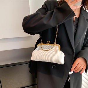 Elegant white pleated handbag with gold metal handle and chain strap on a black suit