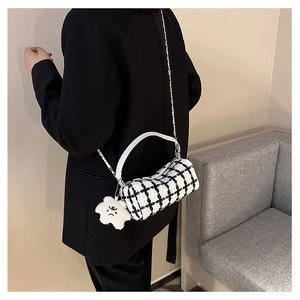 Detail of checkered tweed cylinder bag with white star plush charm and chain strap