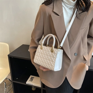 Elegant white quilted square handbag with gold hardware and crossbody strap worn by model