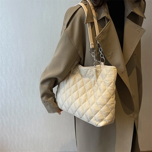 Minimalist white quilted tote bag with silver chain handle shown on a model