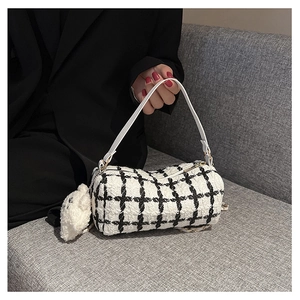 Close-up of black and white plaid cylinder handbag with a cute sheep plush charm