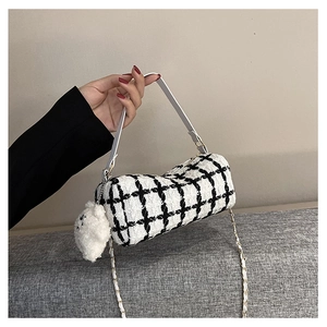 Detail of checkered barrel bag with tweed texture, white handle and cute plush bear charm