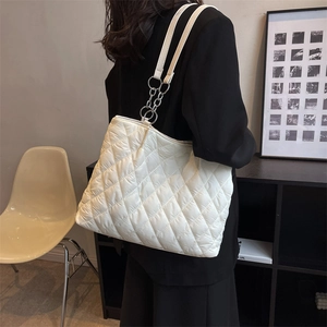 Minimalist white quilted shoulder bag with silver chain strap shown on a model