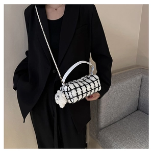 Model wearing a black and white tweed cylinder crossbody bag with a cute plush bear charm