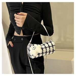 Detail of black and white tweed cylinder crossbody bag with plush star charm and gold chain