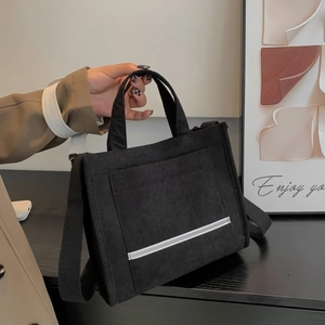 Fashionable black corduroy tote bag with white stripes, versatile for hand or shoulder use