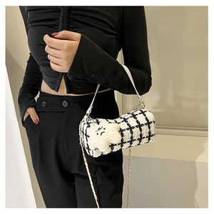 Close-up of black and white checkered cylinder bag with chain and plush cloud charm