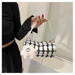 Detail of tweed cylinder bag with black and white plaid pattern and plush star charm