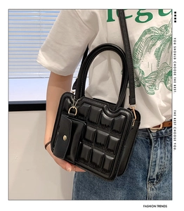 Fashionable black quilted handbag with mini purse charm shown on model in daily use
