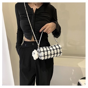Detail of tweed checkered cylindrical bag with chain strap and white bear charm