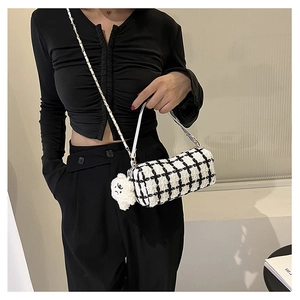 Detail of checkered cylinder bag with plush dog charm and woven chain strap