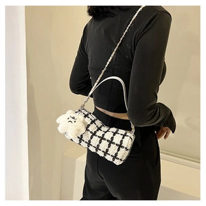 Close-up of black and white plaid tweed bucket bag with plush star charm and dual straps