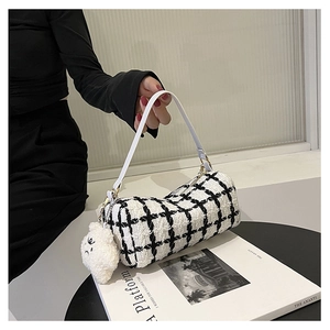 Close-up of black and white plaid tweed cylinder handbag with a plush charm on side