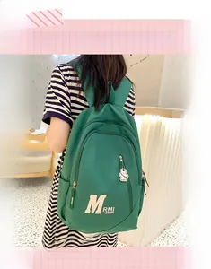Detailed view of dark green nylon backpack with bear charm on striped shirt model