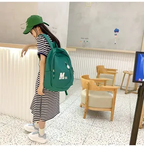 Close-up of green waterproof nylon backpack with white M letter print in a street setting