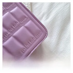 Close-up of lavender quilted faux leather surface with precise stitching on a square bag