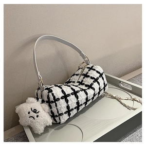 Close-up of black and white plaid cylinder handbag with star plush charm and chain strap