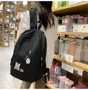 Detail of classic black nylon backpack showing M RMI print and cute bear keychain