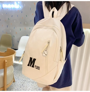 Detailed view of white canvas backpack with black letter print and cute bear keychain