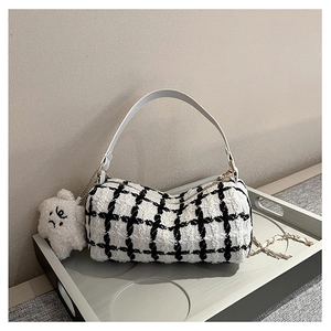 Detail of checkered tweed cylinder bag with white leather handle and plush star charm