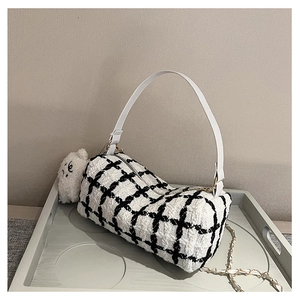 Detailed macro view of black and white checkered tweed material and chain strap on the bag