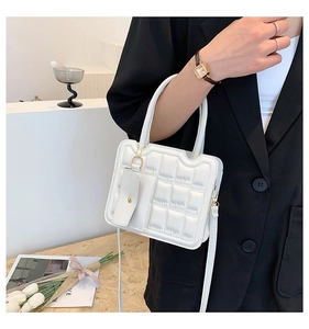 Detail of white quilted handbag with a matching small card holder and gold hardware accents