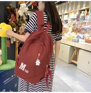 Close-up of burgundy nylon backpack with MRMI logo and white bear keychain accessory