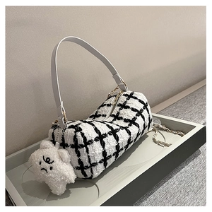 Detail of tweed checkered cylinder handbag with gold zipper and plush cartoon charm
