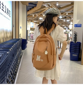Close-up of orange vintage school backpack with bear pendant in shopping mall scene