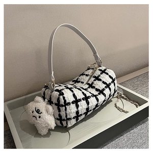 Detail of tweed cylinder bag with black plaid pattern and cute white plush bear charm