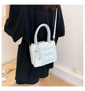Detail view of a white quilted crossbody bag with a small matching coin purse accessory