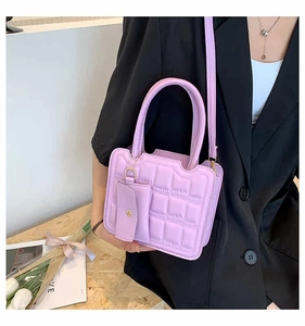 Detail of lilac quilted crossbody bag with matching coin purse on black blazer