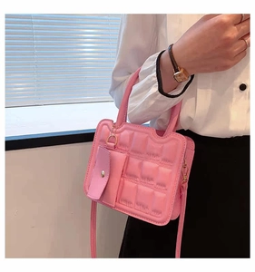 Pink quilted crossbody bag with matching coin purse shown held by a model in casual attire