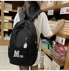 Detailed close-up of a black vintage backpack featuring a white bear charm and side pocket