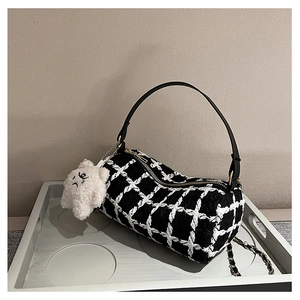 Close-up of black and white plaid tweed cylinder bag with plush star charm and gold zipper