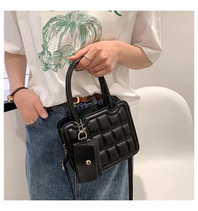 Detail of black quilted tote bag with wave opening and matching mini coin purse accessory