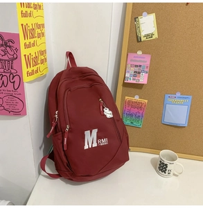 Detail of burgundy vintage backpack with side zipper pocket and cute white bear keychain