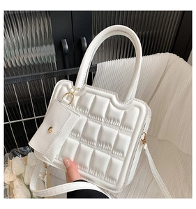 Close-up of a white waffle-patterned handbag with quilted texture and a mini coin purse